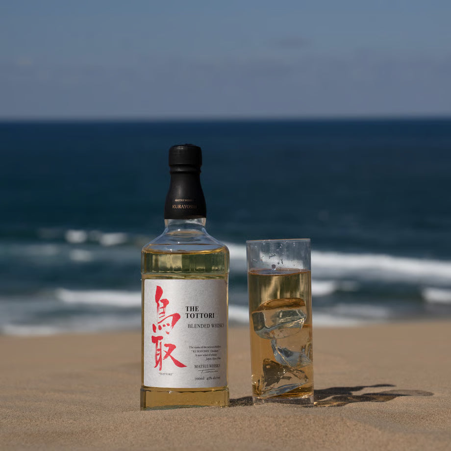 「マツイ ブレンデッドウイスキー 鳥取 銀ラベル」のボトルとグラスの写真。鳥取の海を背景に撮影され、軽やかな飲み心地が特徴のウイスキー。