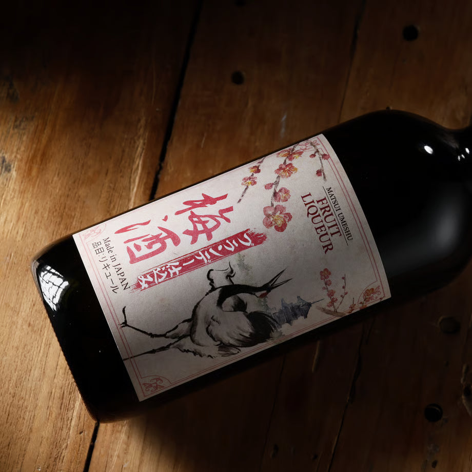 木の上に置かれたマツイ梅酒のボトル。国産梅とブランデーを使った、華やかで濃厚な味わいの梅酒。