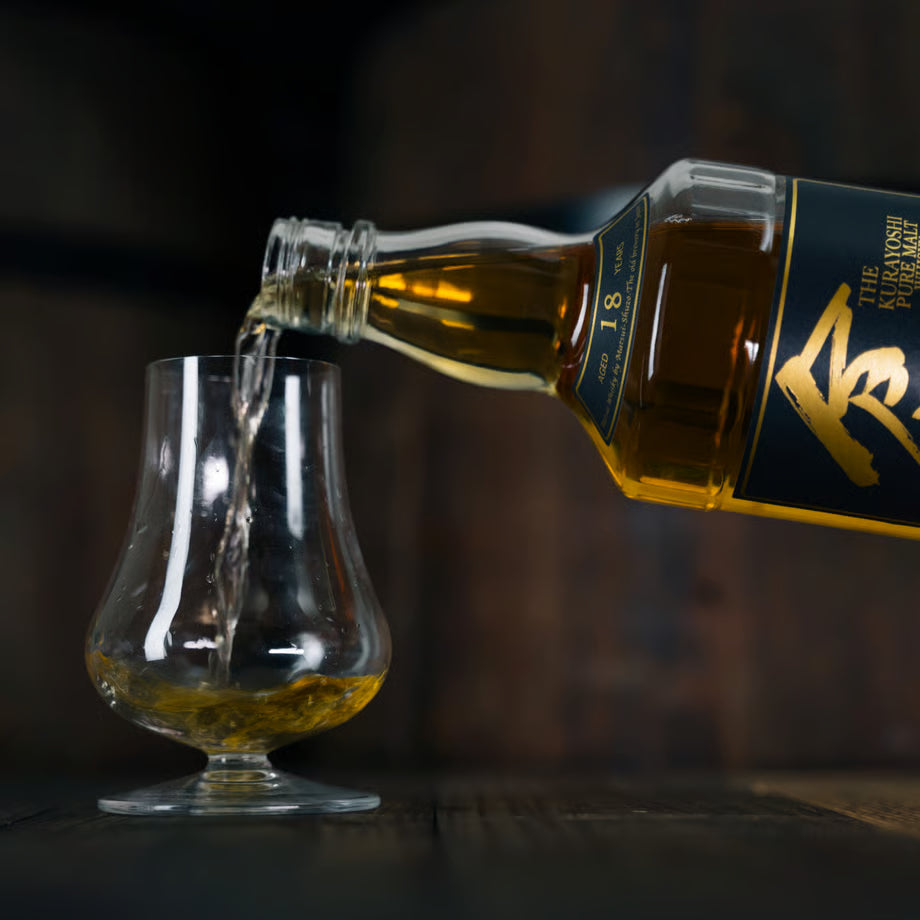 マツイピュアモルトウイスキー「倉吉18年」をグラスに注いでいる様子を写した写真。深みのある琥珀色や18年表記のラベルが確認できる。