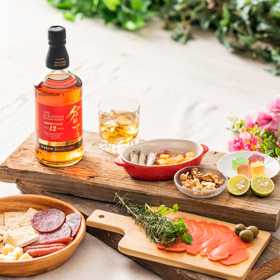 マツイブレンデッドウイスキー「倉吉 シェリーカスク12年」と、前菜やナッツを並べたテーブルシーン。シェリー樽由来の香味を持つ12年熟成ウイスキー。