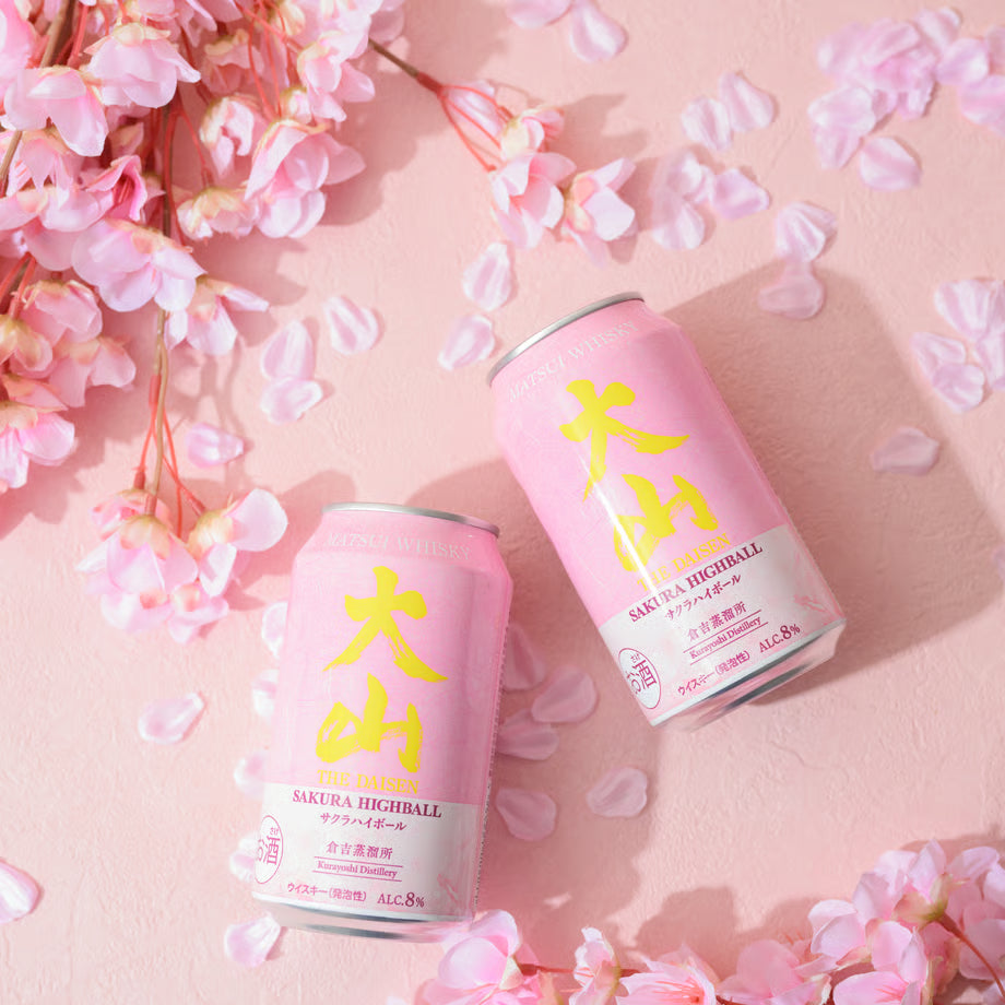 桜の花びらが散る淡いピンクの背景に、大山サクラハイボールの缶が二本並ぶ春らしい演出の写真。