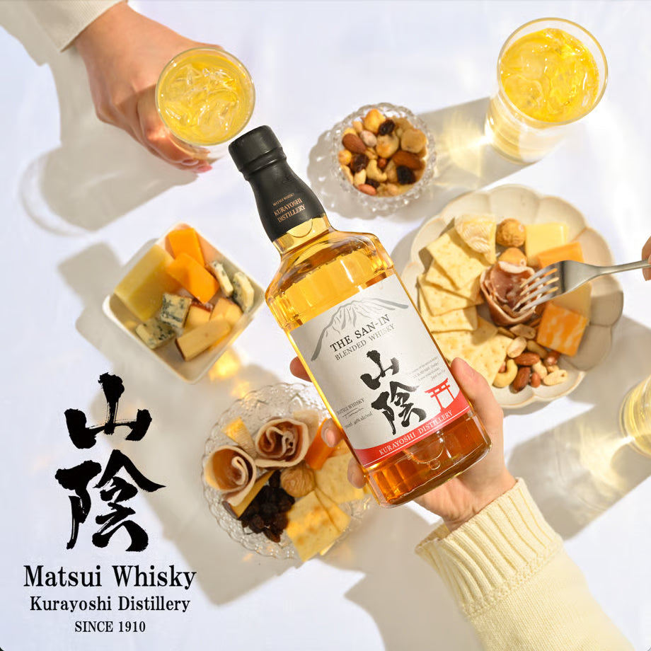 チーズやナッツを囲む食卓で「山陰」ブレンデッドウイスキーを手に持つシーン。食事と合わせやすい軽やかな口当たりのウイスキー。