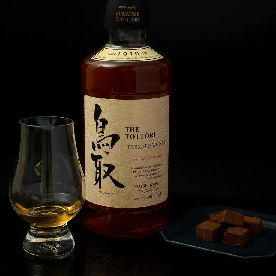 マツイブレンデッドウイスキー「鳥取 金ラベル」のボトルとテイスティンググラスが並ぶ写真。モルトとグレーン原酒を合わせ、バニラのような香りを感じられるウイスキー。