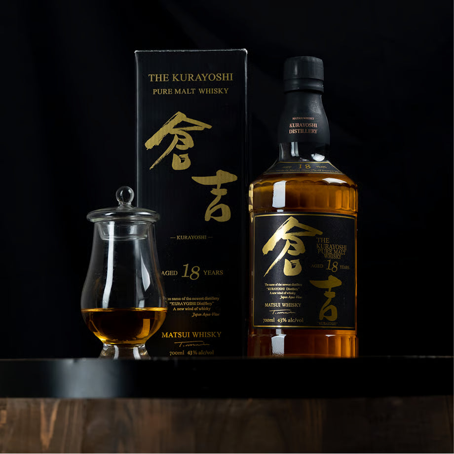 マツイピュアモルトウイスキー「倉吉18年」のボトルと化粧箱、テイスティング用グラスが並ぶ写真。黒と金を基調とした上質なデザインが際立っている。