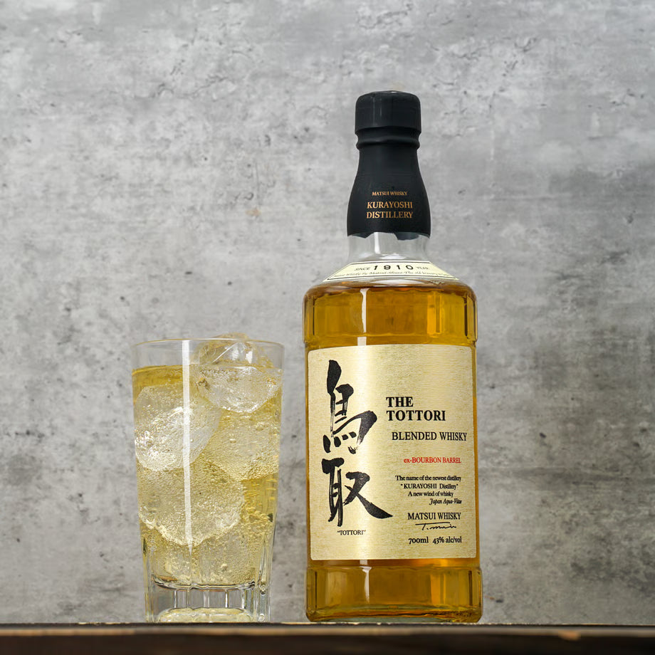 マツイブレンデッドウイスキー「鳥取 金ラベル」のボトルと氷入りハイボールが並ぶ写真。モルトとグレーン原酒を合わせ、バニラやキャラメルの香りが特徴のウイスキー。